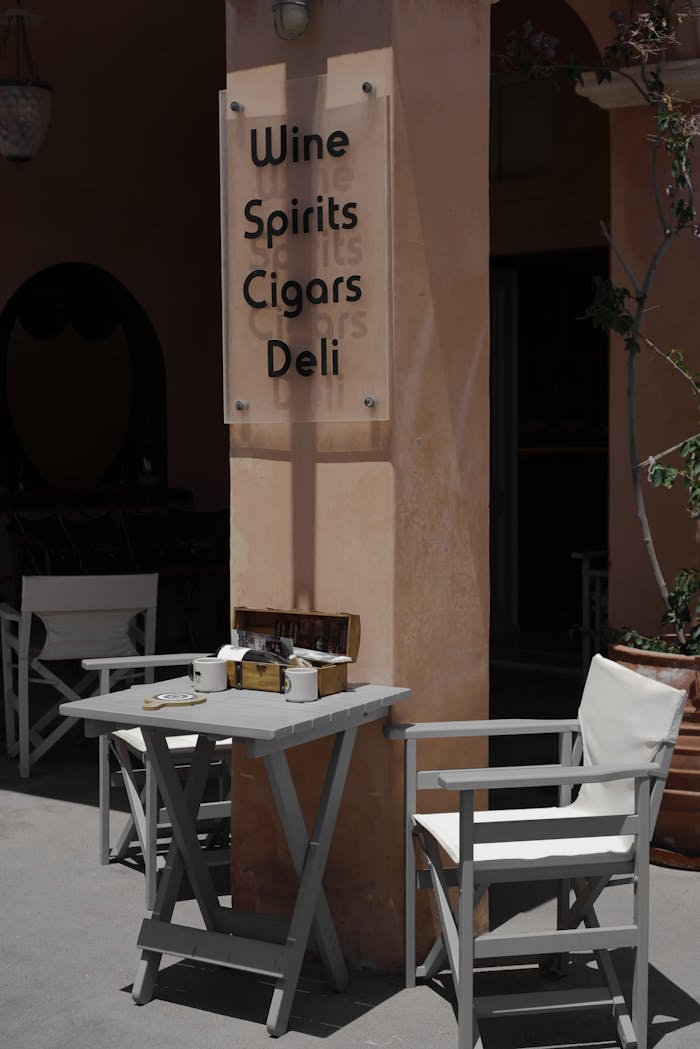 Small outdoor table setup at a wine and cigar shop with chairs.